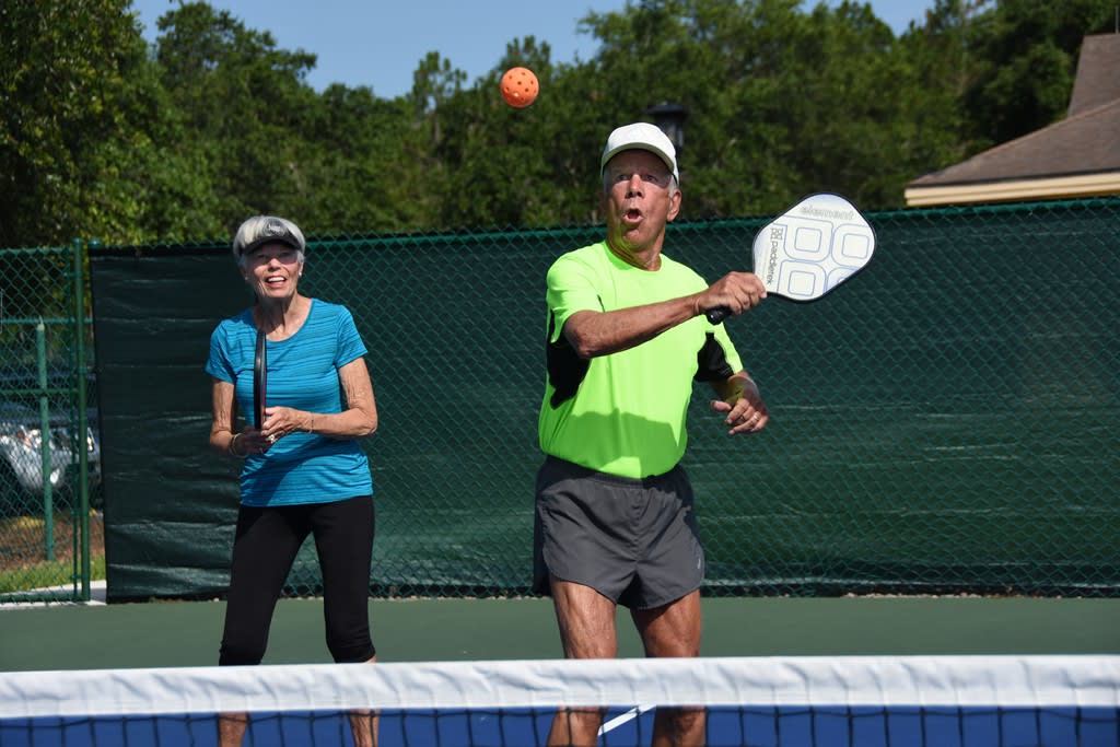 A couple playing pickleball outdoors on a sunny day.