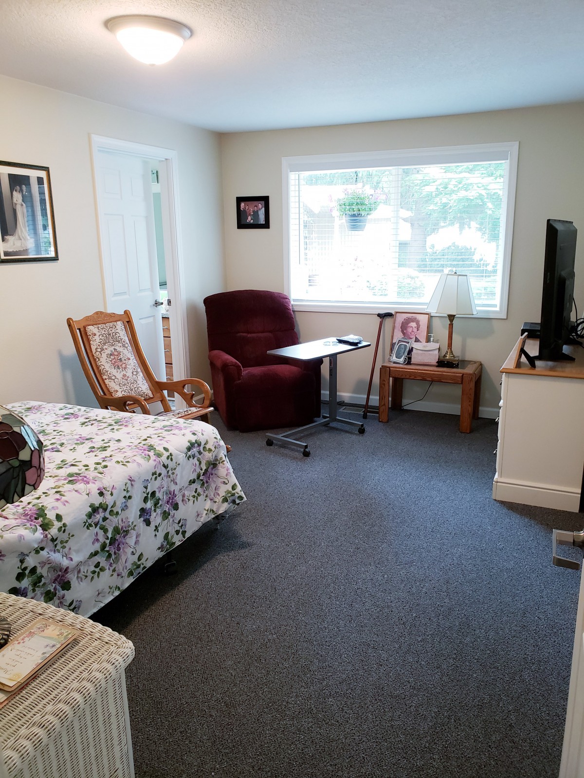 A cozy living room with a bed, armchair, television, and window offering a view.