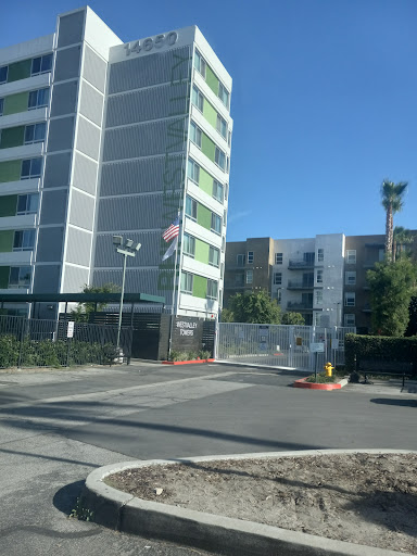 A view of a modern apartment building with a gated entrance and an American flag.