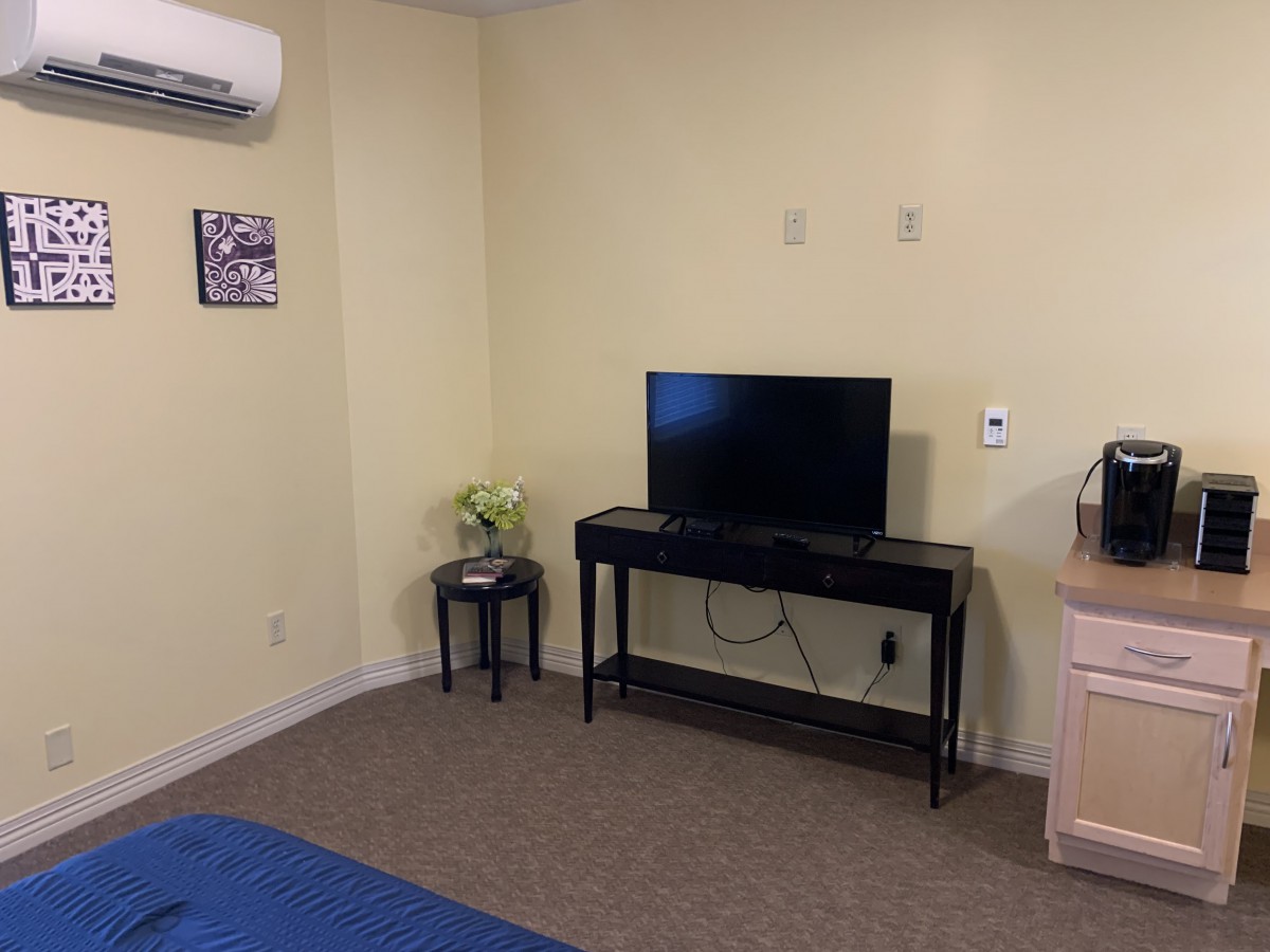 A minimalist hotel room with a television and air conditioning unit.