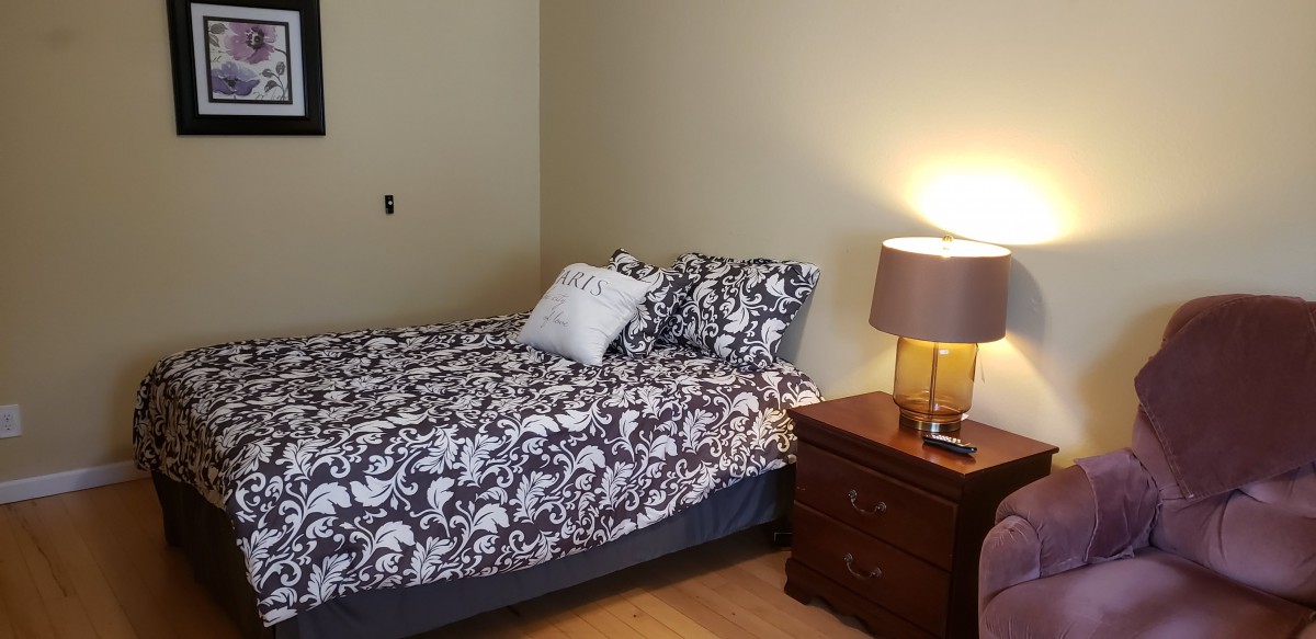 A cozy bedroom with a patterned bedspread and a nightstand with a lamp.