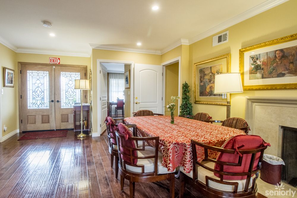 A warm and inviting dining room with a long table and chairs, decorated with artwork and bright lighting.