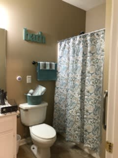 A bathroom with a floral shower curtain and neatly arranged towels.