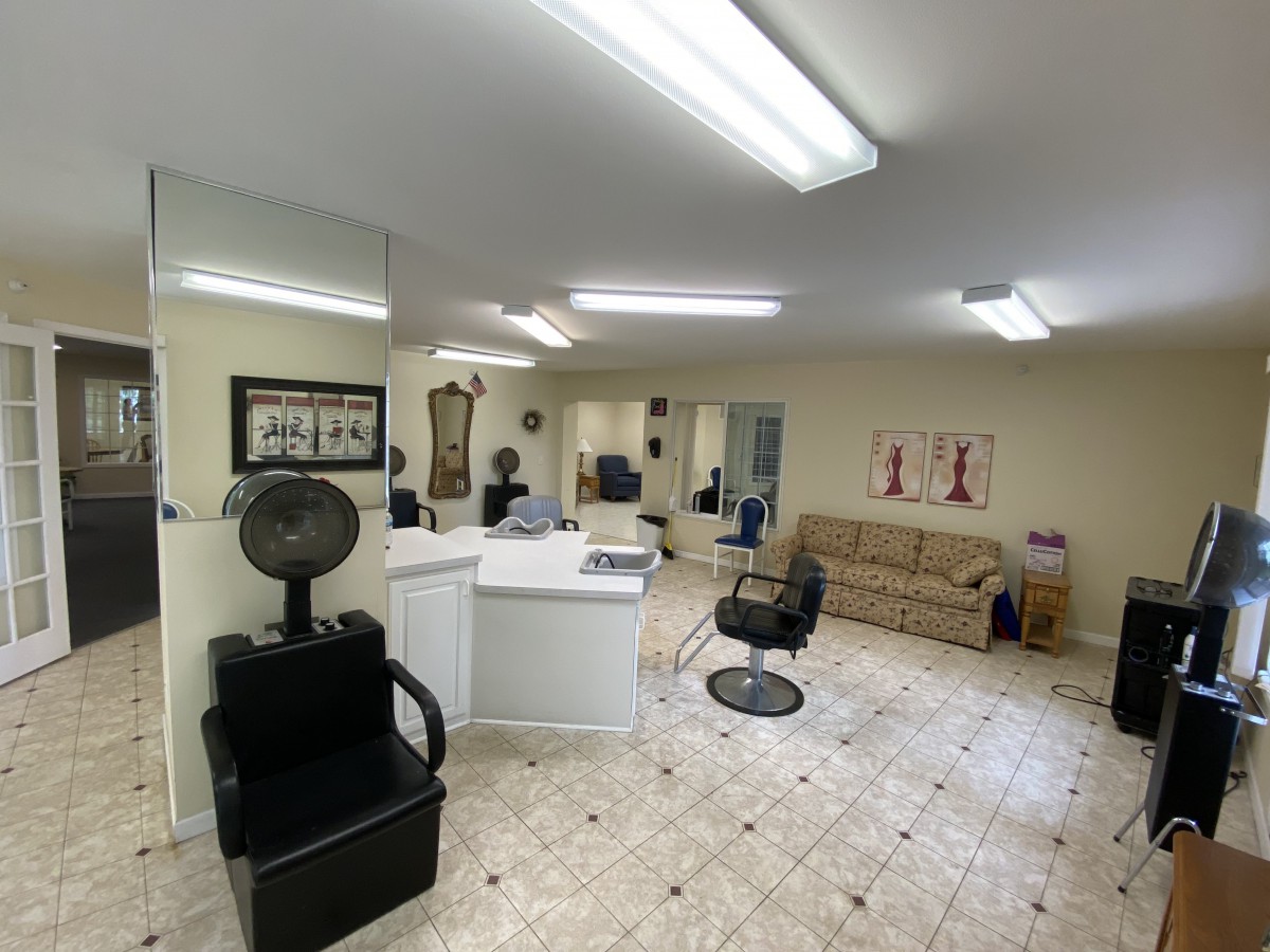 A well-lit hair salon interior featuring styling chairs, mirrors, and a comfortable waiting area with a sofa.
