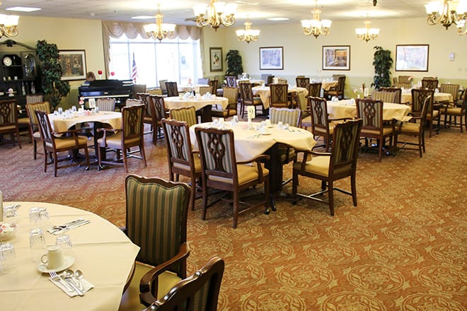 An elegant dining room with neatly arranged tables and chairs, featuring warm lighting and tasteful decor.