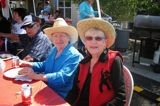 Two women enjoying a sunny day at an outdoor event, both wearing stylish hats.