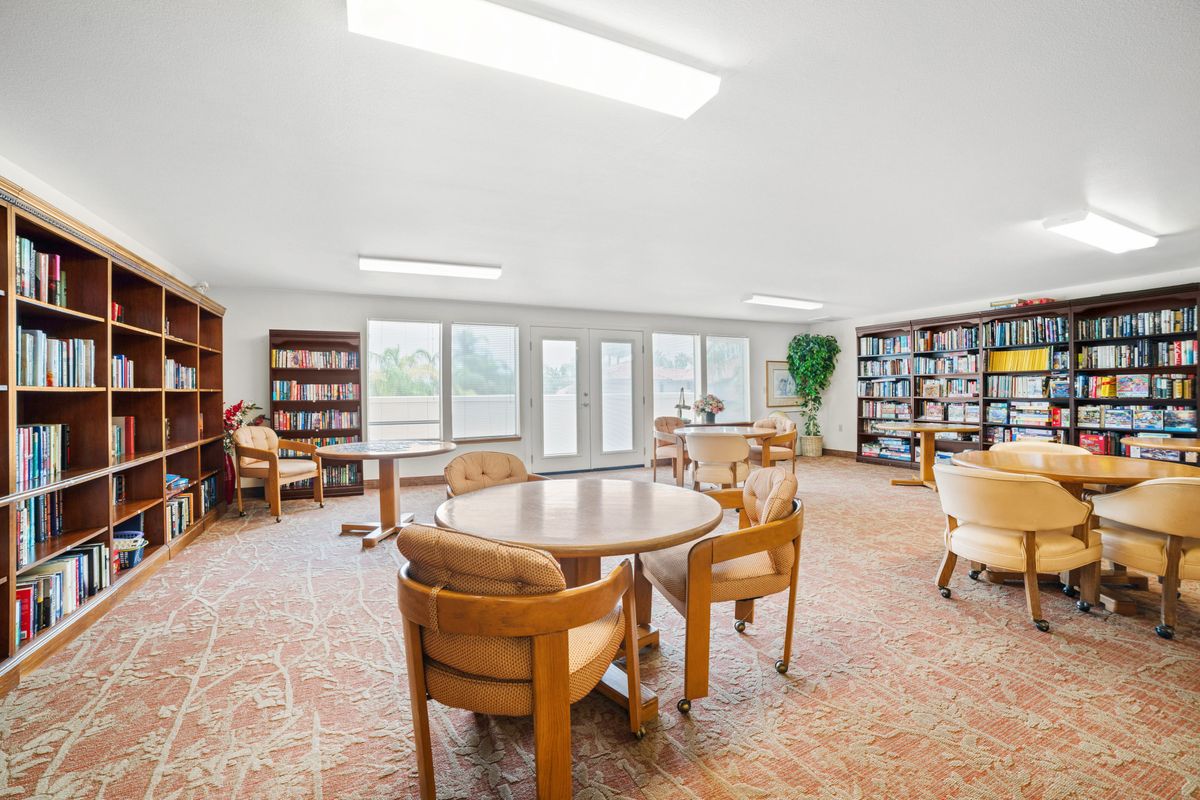 A spacious library reading area with round tables and bookshelves.