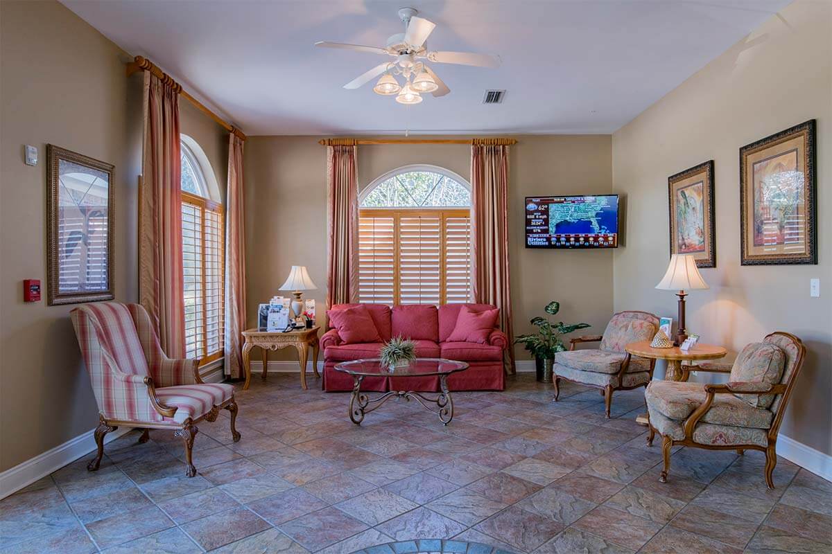 A cozy living room with a red sofa, elegant chairs, and a mounted television.