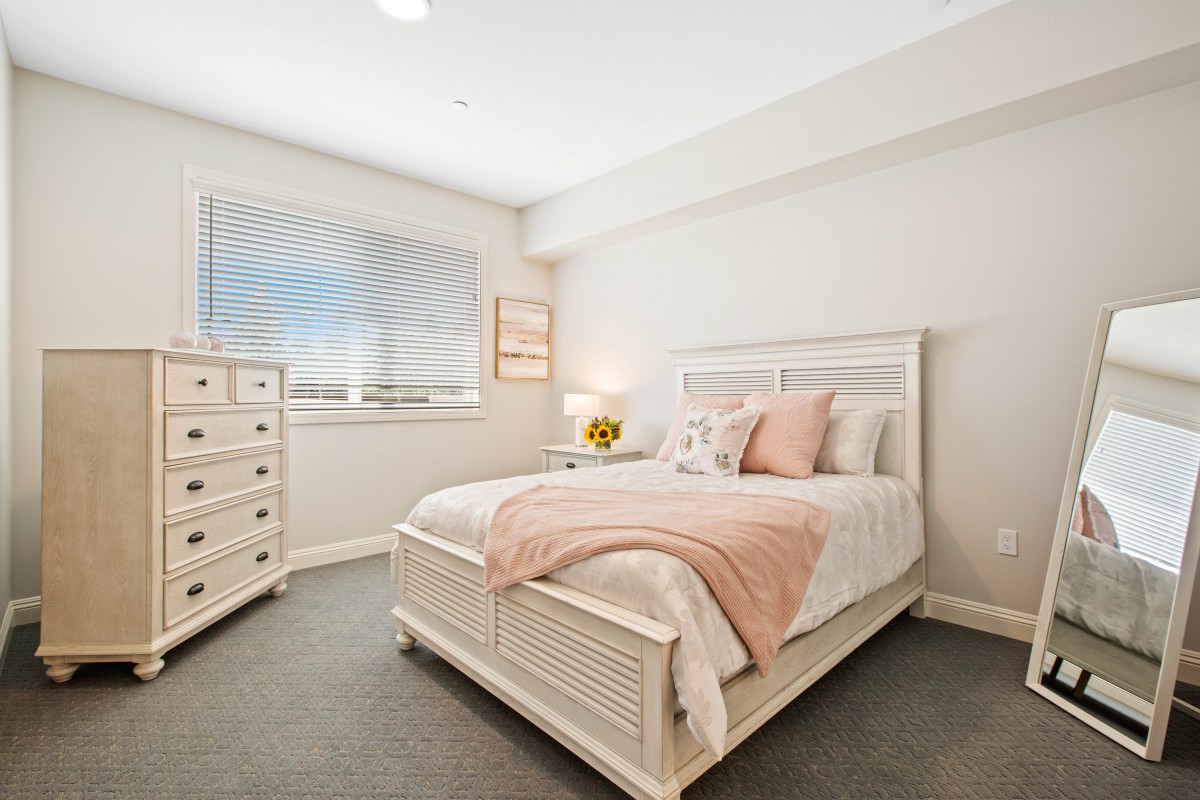 A cozy bedroom with neutral tones featuring a bed and dresser.