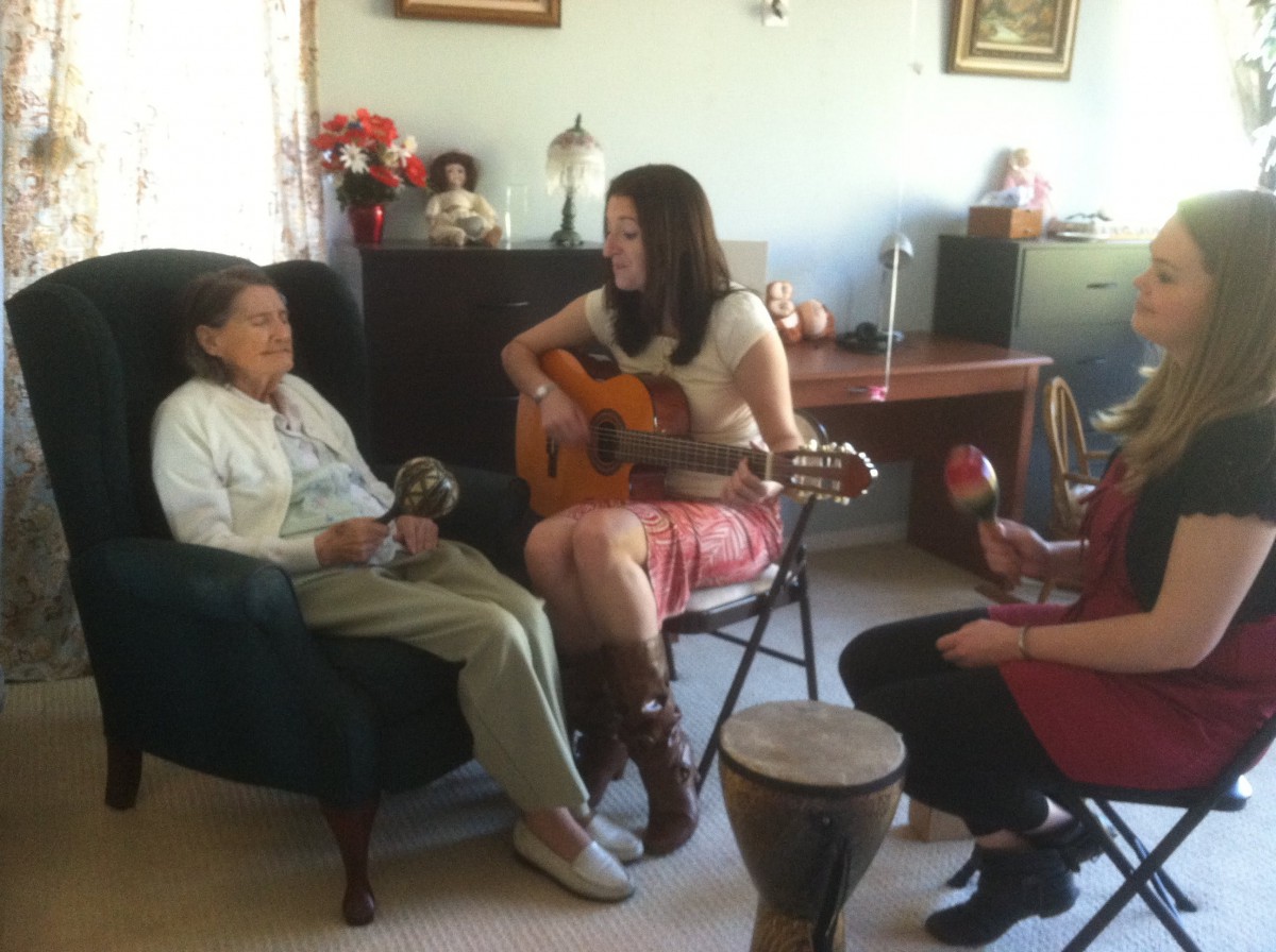 A family gathering where one person plays the guitar while others join in with percussion instruments.