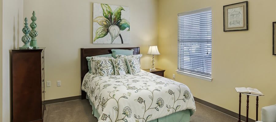 A cozy bedroom with floral bedding and a decorative lamp beside the bed.