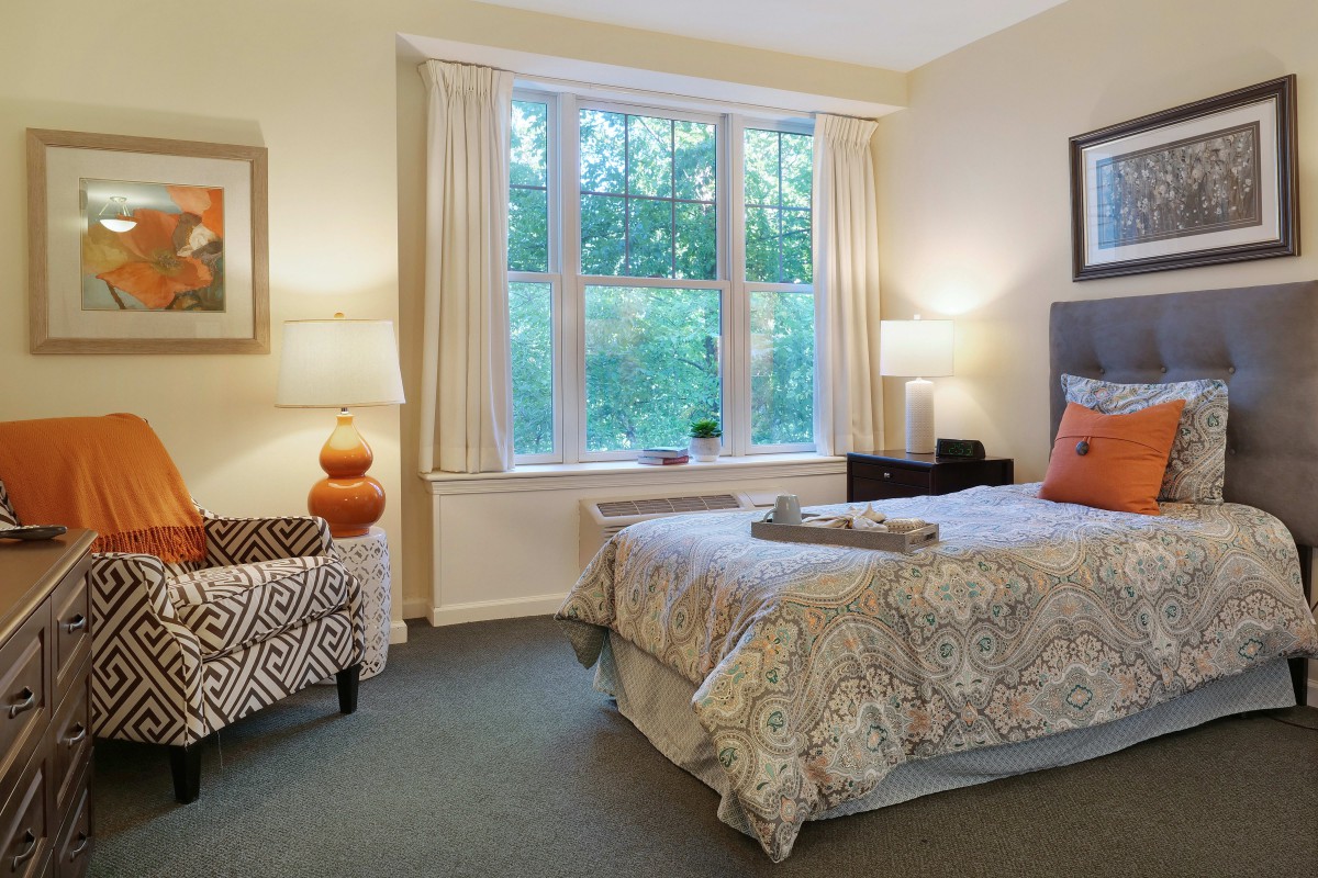 A cozy bedroom with a large window, bed, and elegant decor.