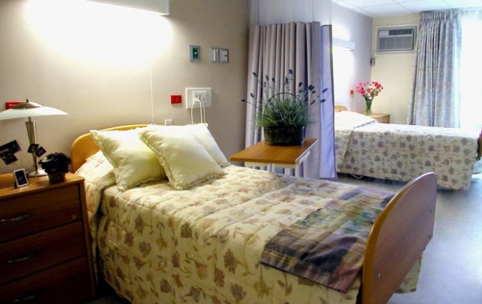 A clean and comfortable hospital room with two beds, curtains, and floral decor.