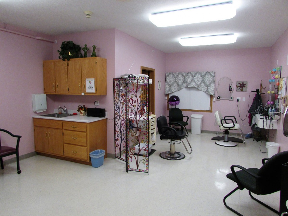 An interior view of a hair salon with pink walls, equipped with styling chairs and beauty equipment.