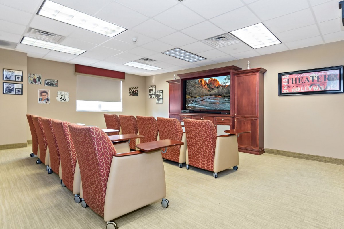 A modern conference room with comfortable seating and a large television.