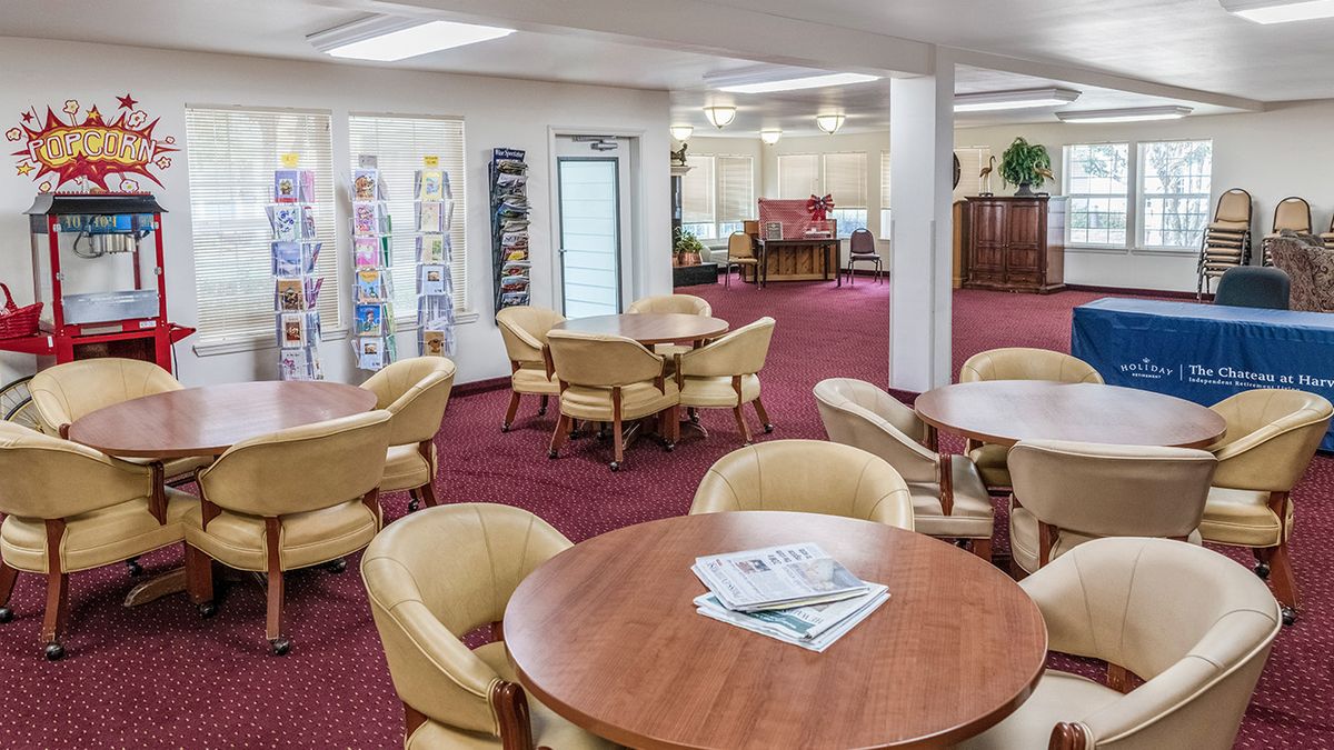 A cozy lobby with seating areas featuring round tables and beige chairs on a red carpet.