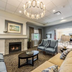A cozy living room with a fireplace, elegant chandelier, and comfortable seating.