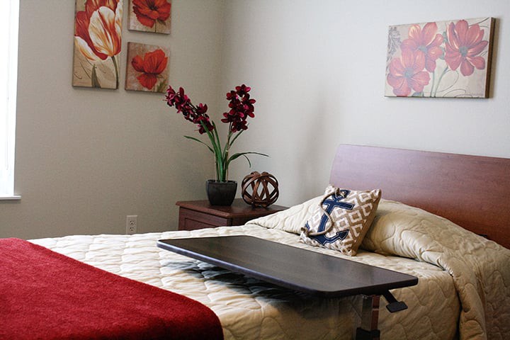 A cozy bedroom with a neatly made bed, decorative pillows, and vibrant wall art.
