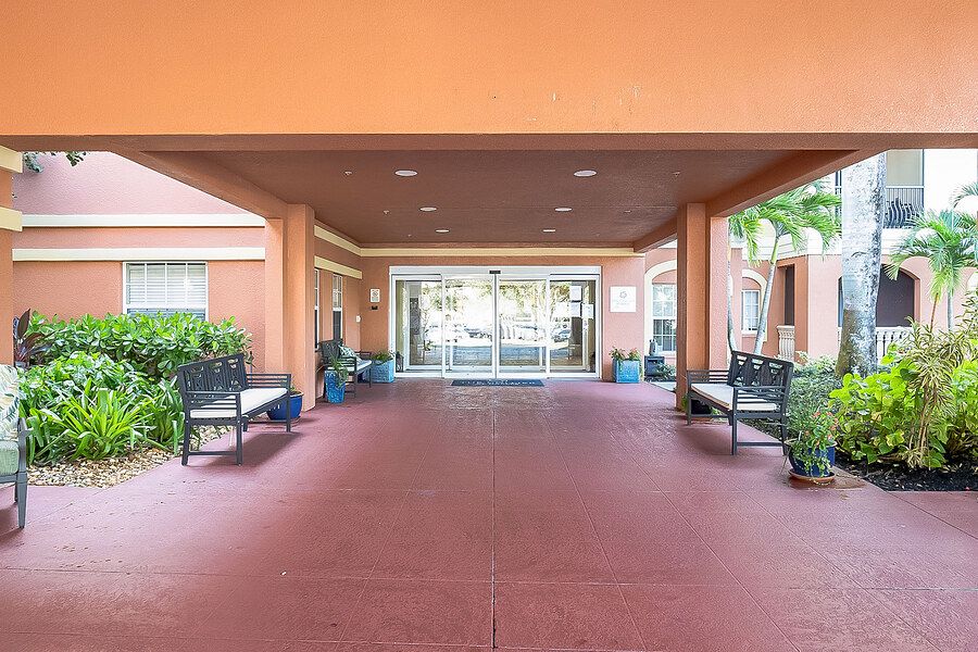 A covered building entrance with benches and potted plants.
