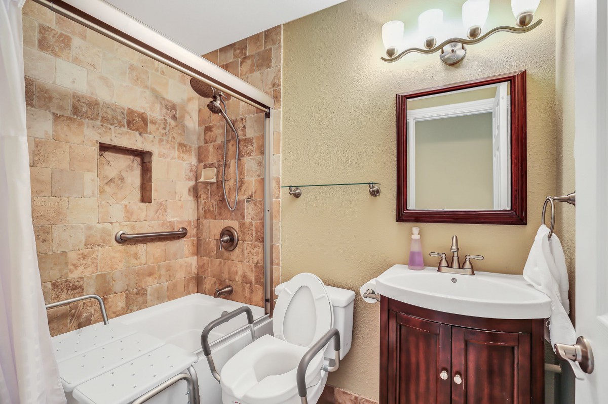 A well-equipped bathroom with a bathtub, toilet, sink, and accessible features.