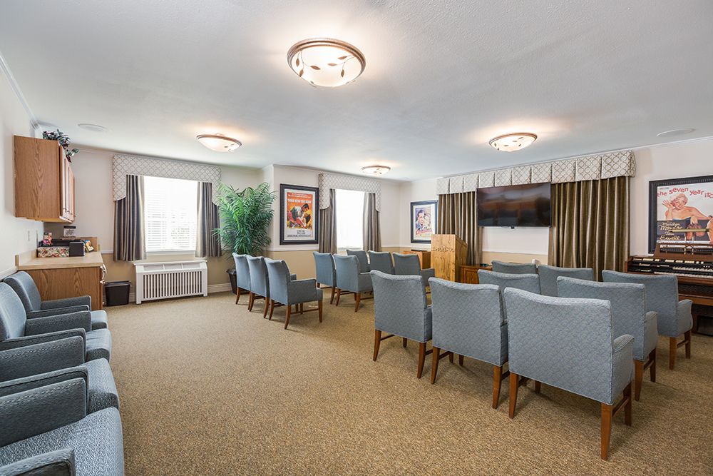 A neatly arranged conference room with rows of chairs facing a podium and projector screen.