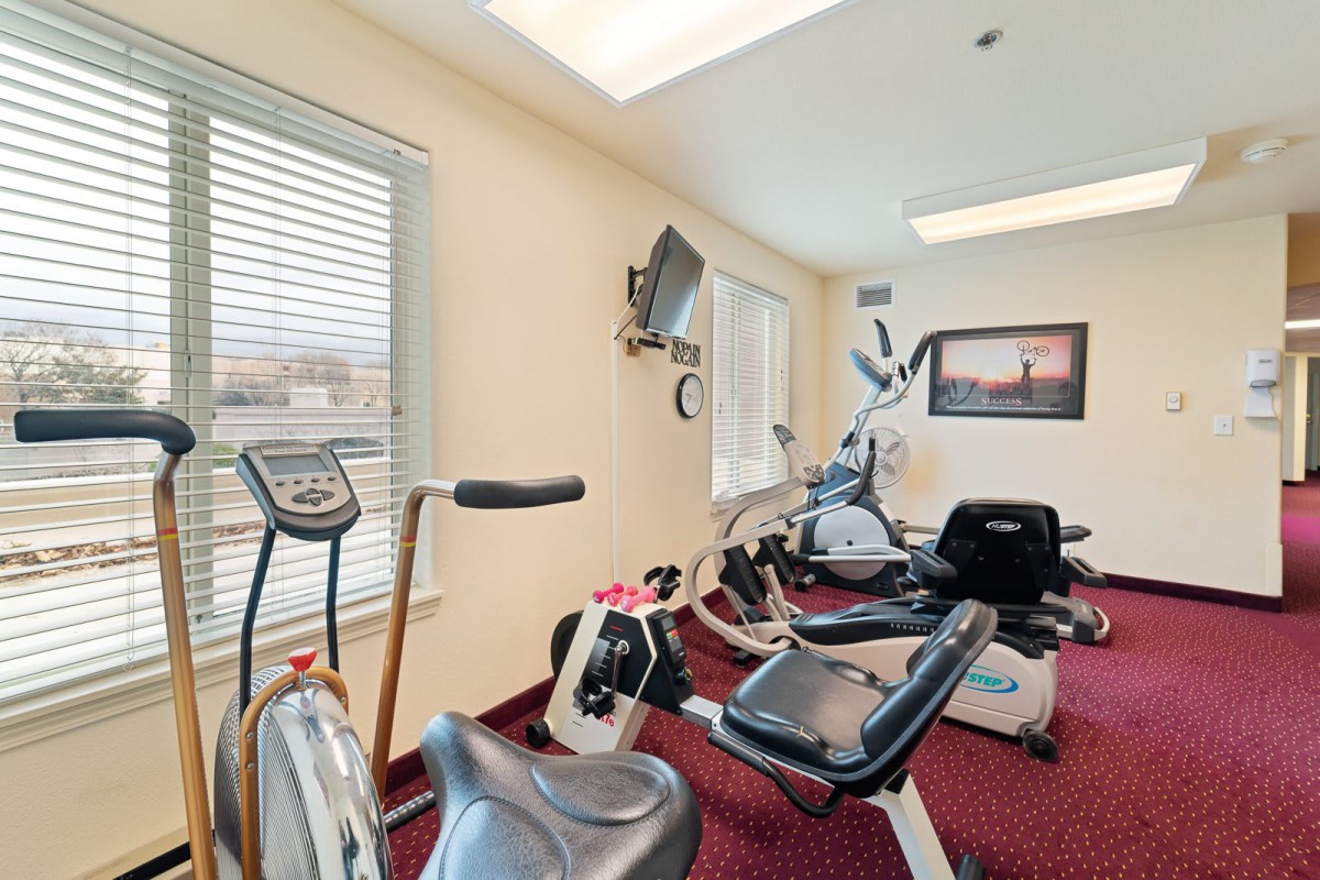 A fitness room with various exercise equipment, including cardio machines.