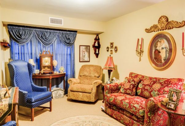 A cozy vintage-style living room featuring a patterned sofa, armchair, and ornate decor.