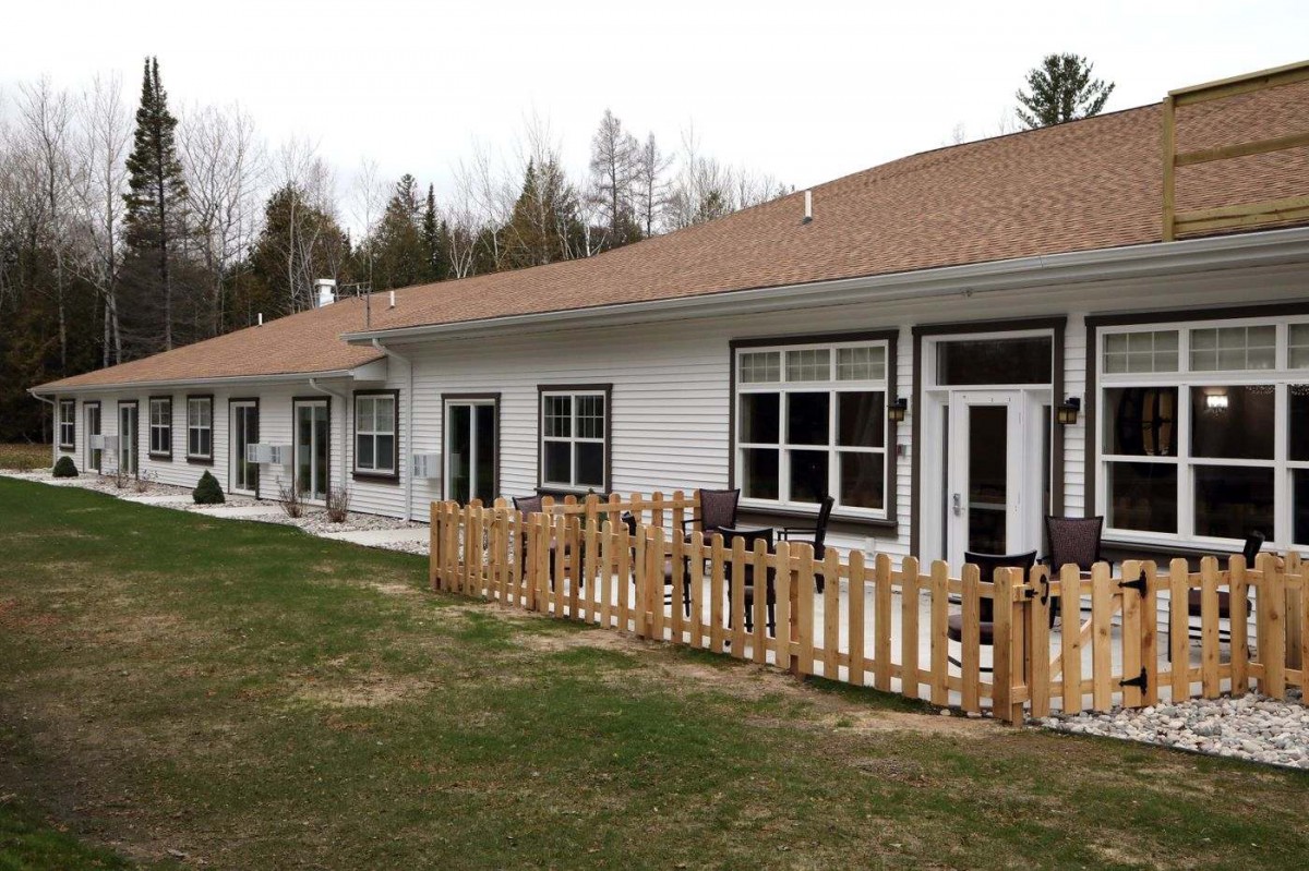 A row of single-story homes with a wooden fence and grassy lawn.