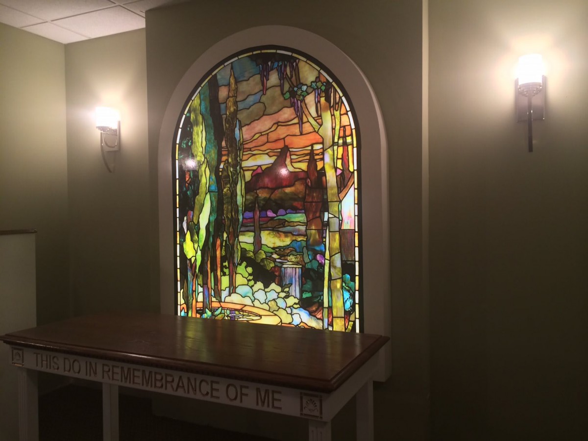 A beautifully crafted stained glass window set in a softly lit interior space.