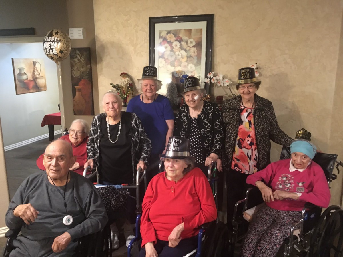 A group of elderly people celebrating with party hats indoors.