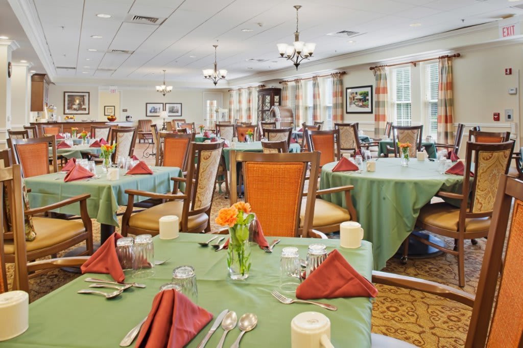 A well-decorated dining area with neatly arranged tables and chairs, featuring elegant table settings.