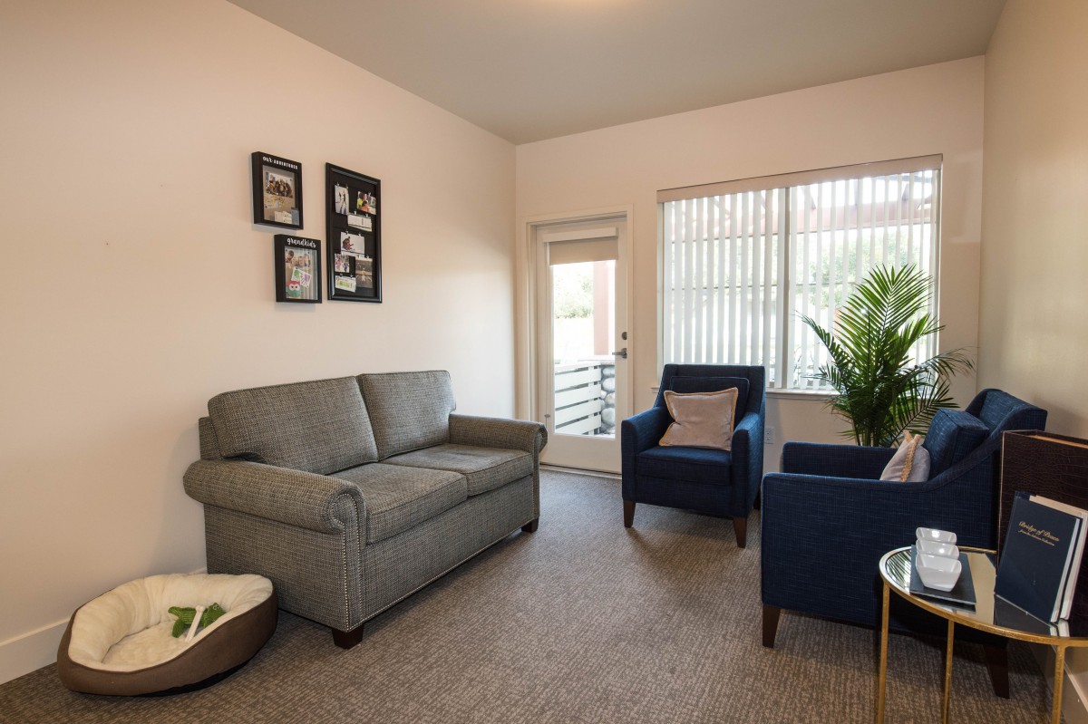 A cozy living room with a gray sofa, two blue armchairs, and a large window.