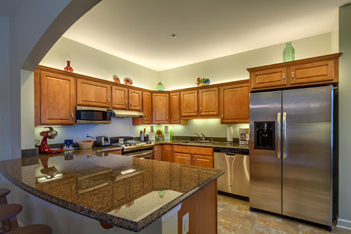 A beautifully designed modern kitchen featuring wooden cabinets, stainless steel appliances, and elegant granite countertops.