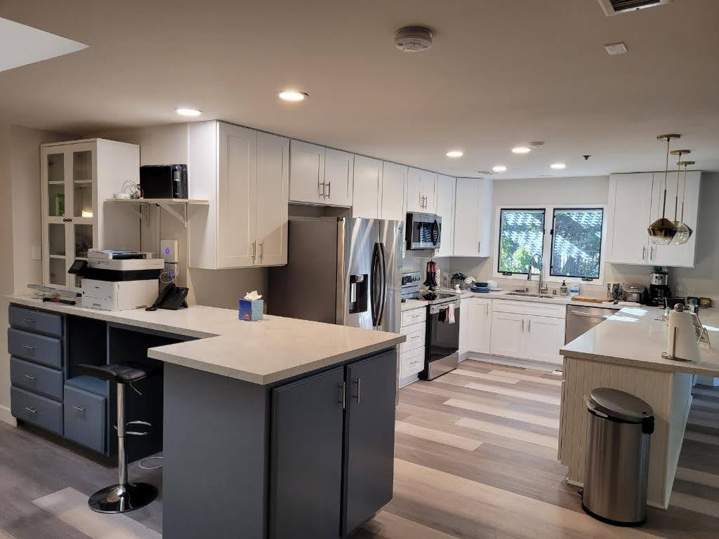 A modern kitchen with an island, white cabinets, and wood flooring.