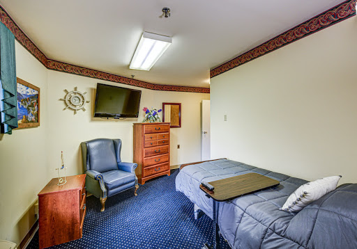 A cozy room featuring a bed, comfortable chair, TV, and storage options.