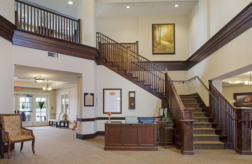 A spacious and elegant hotel lobby with a reception desk and wooden staircase.