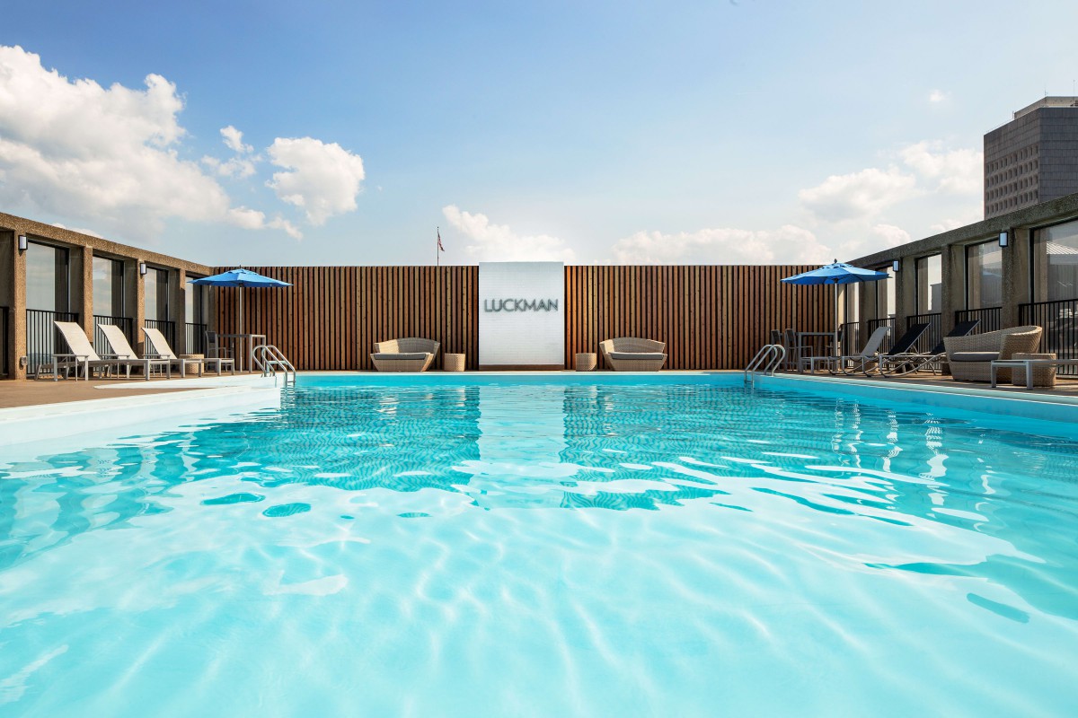 A serene outdoor swimming pool with deck chairs and sun umbrellas under a clear blue sky.