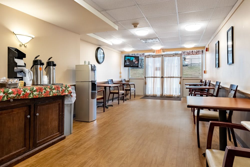A cozy indoor dining area with tables, chairs, a television, and a coffee station.