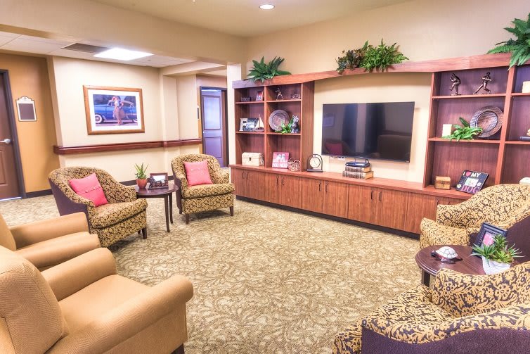 A cozy and well-decorated living room with comfortable seating, a large television, and ornamental shelves.