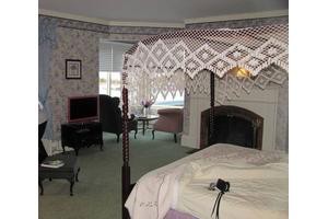A traditional bedroom interior with a cozy fireplace and elegant furnishings.
