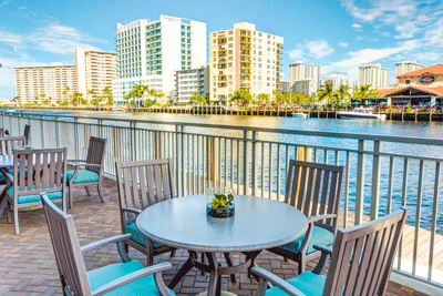 A scenic view of a waterfront patio overlooking tall city buildings under a clear blue sky.