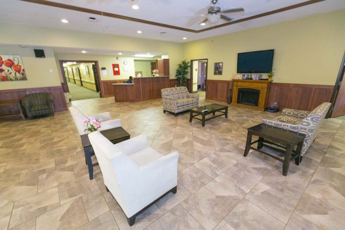 A spacious lobby area featuring comfortable seating, a reception desk, and a television mounted above a fireplace.
