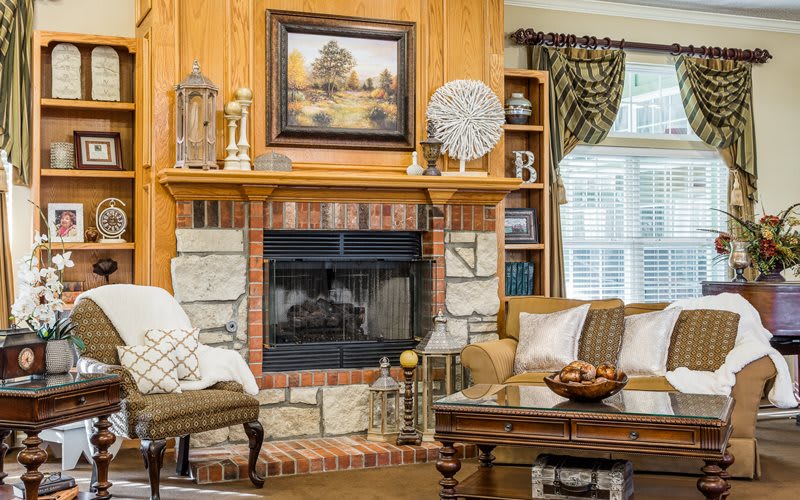 A cozy living room featuring a brick and stone fireplace, surrounded by comfortable furniture and elegant decorations.