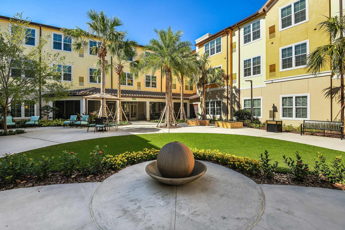 A well-maintained courtyard with palm trees and a fountain feature, surrounded by a residential building.