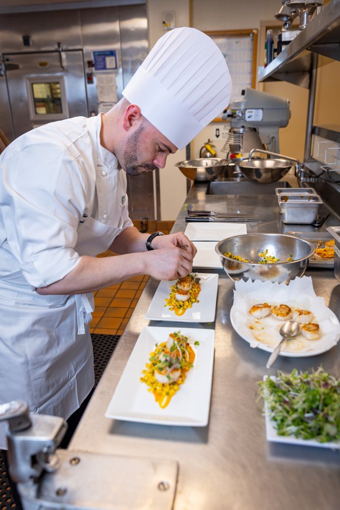 A chef meticulously plating a gourmet dish in a professional kitchen.