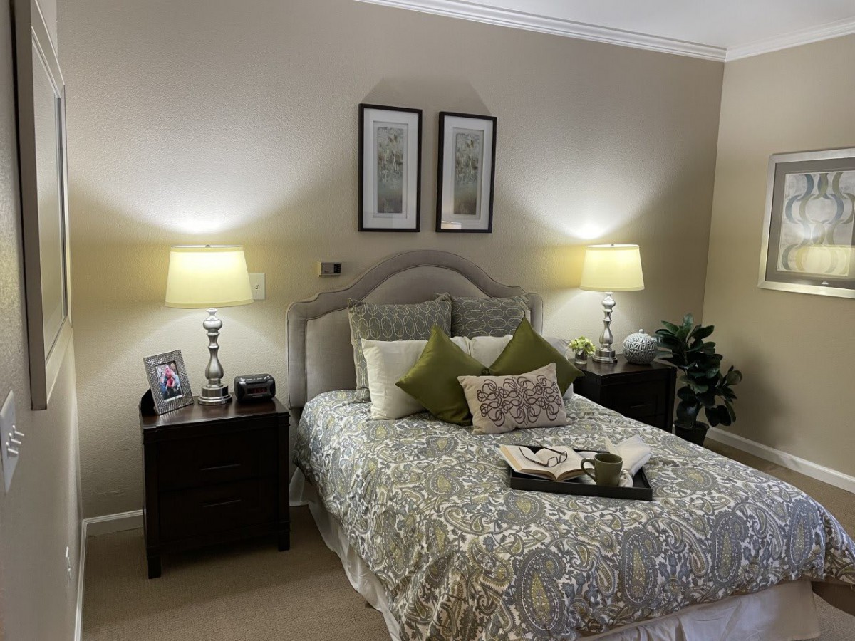 A cozy bedroom with elegant decor, featuring a neatly made bed, decorative pillows, and soft lighting from matching lamps on nightstands.