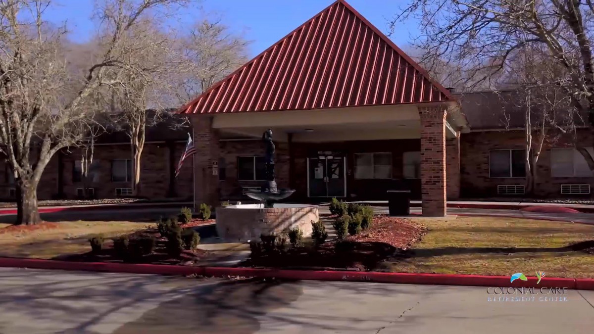 A brick building with a red roof and landscaped entrance.