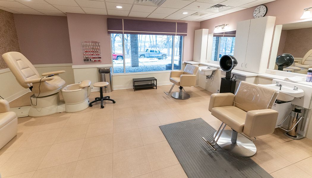A modern hair salon interior with chairs, mirrors, and a dryer near the window.