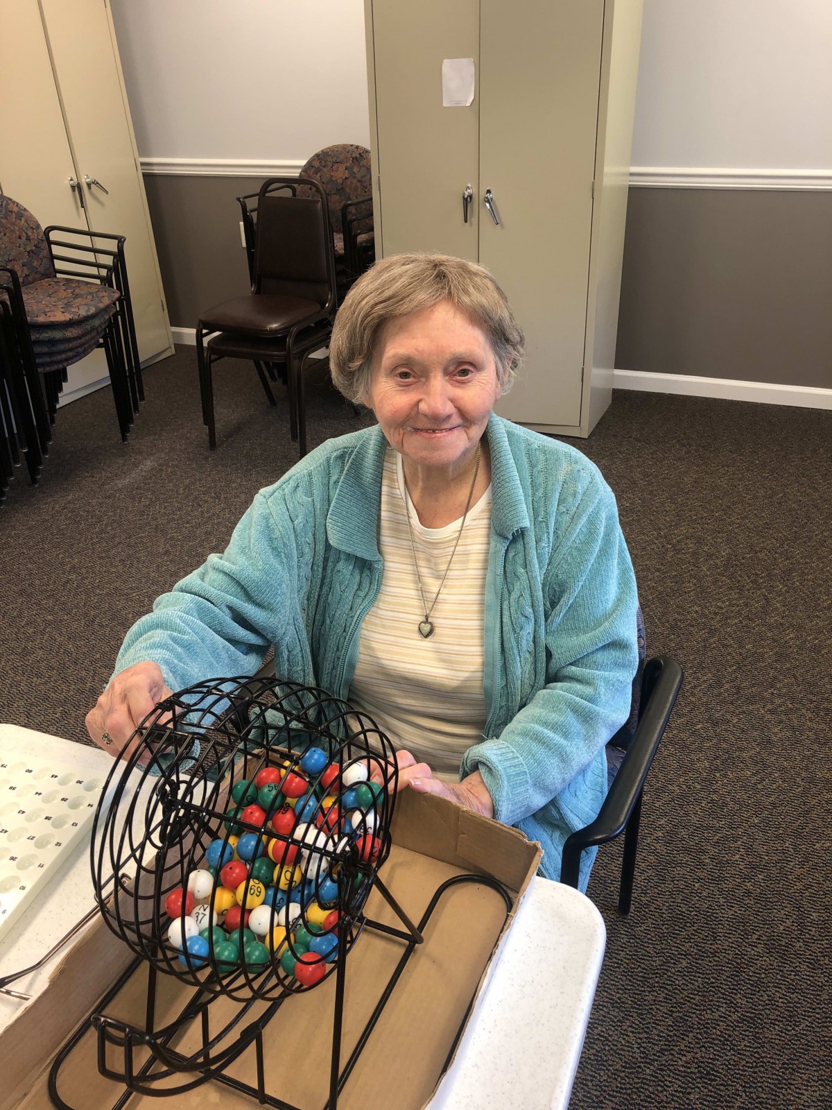 An elderly woman smiling while playing bingo indoors.