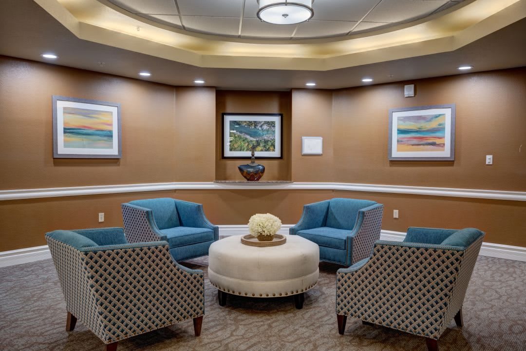 A modern waiting room with blue chairs, a central round table, and artwork on the walls.